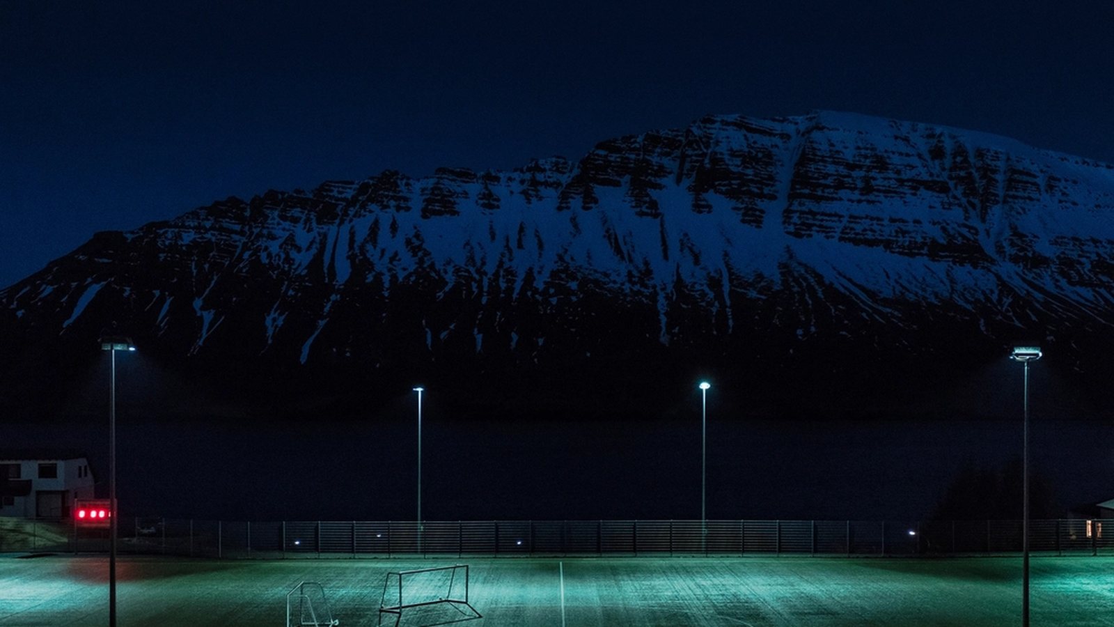 Floodlit football pitch at night, illustrating the persistent social hub concept behind The Grounds in EA Sports FC 27